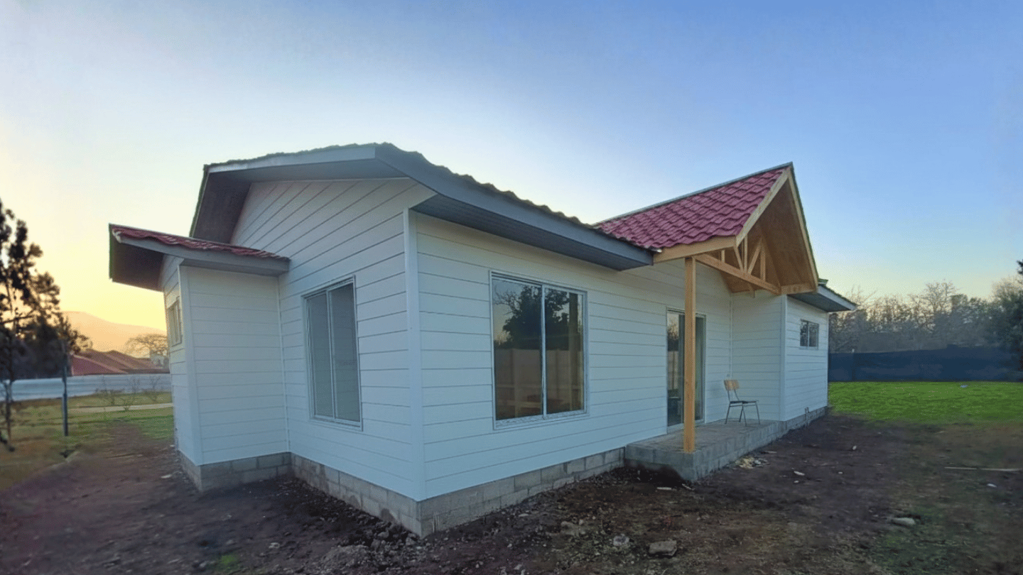Vivienda de fachada clara y pórtico de madera al atardecer, de la galería de Órdenes Construcciones