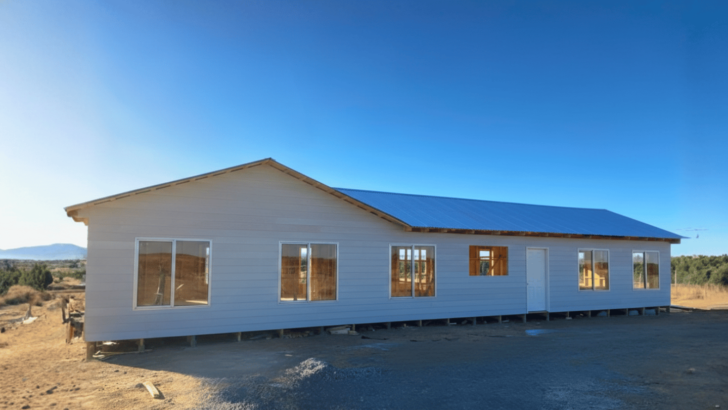 Vivienda amplia de fachada clara y grandes ventanales en un entorno rural, de la galería de Órdenes Construcciones
